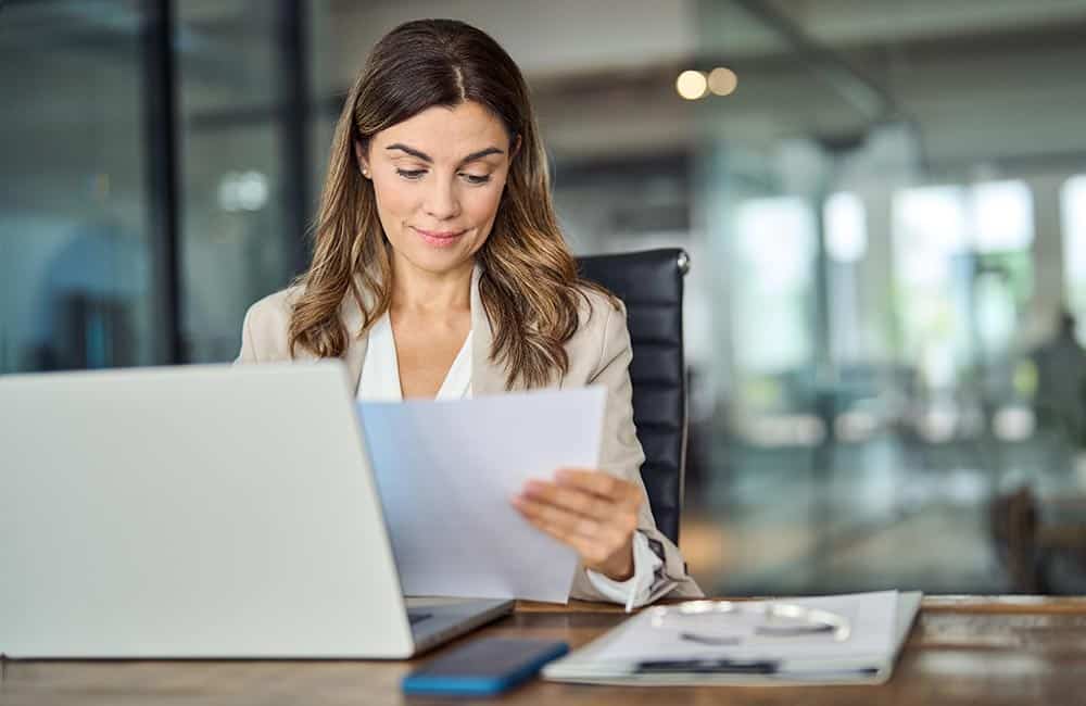 Lawyer reviewing a document while tracking time on their laptop.