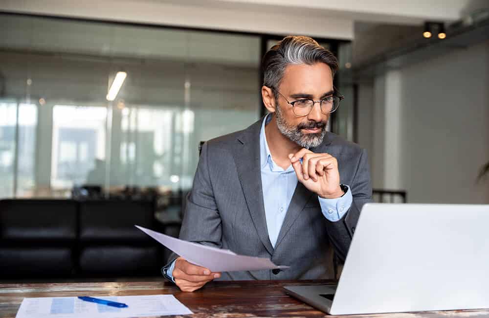 lawyer sitting at his desk and looking over his trust account transactions on his computer